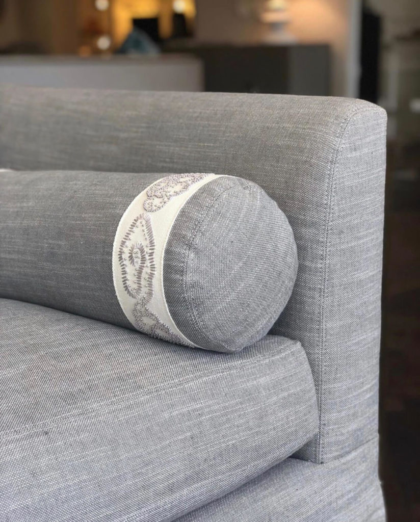 A custom pillow trimmed with Samuel & Sons China Cloud Embroidered Border seen on a sofa at Ferrell Mittman in New York City.