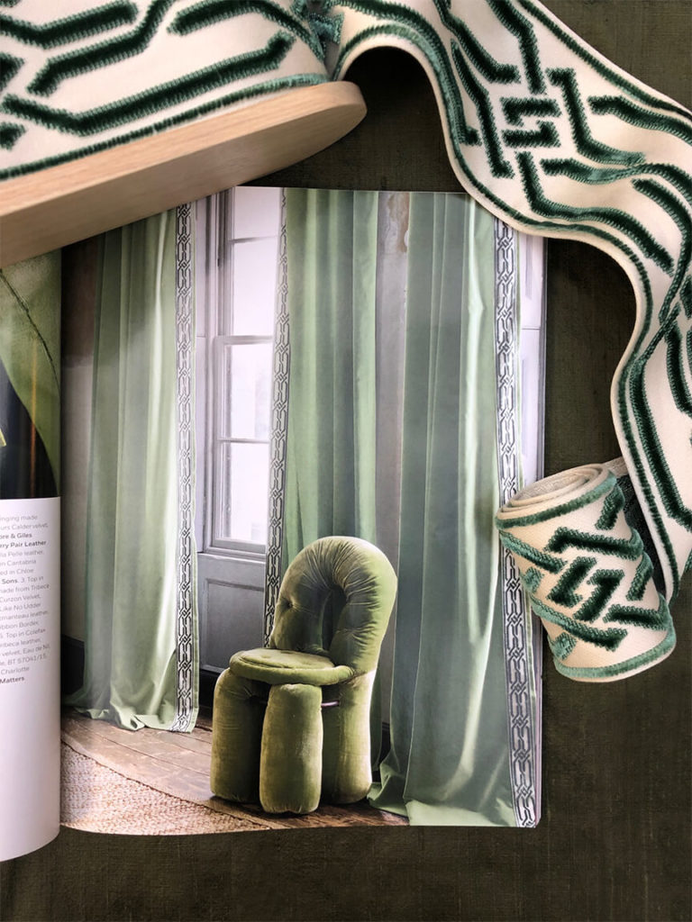 An epingle border from Samuel & Sons is seen on the pages of Milieu magazine trimming the leading edge of green draperies.
