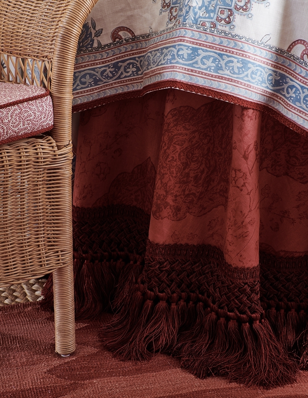 A table skirt with tassel fringe and a chair with a red and white fabric, adding a touch of vibrant colors to the room's decor.